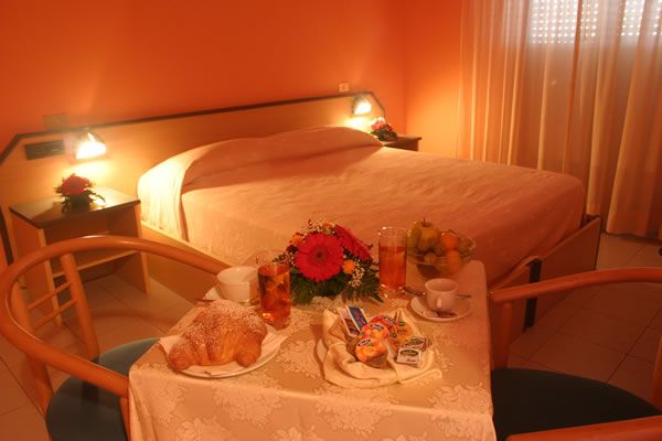 Camera d'albergo con letto matrimoniale e colazione su un tavolino.