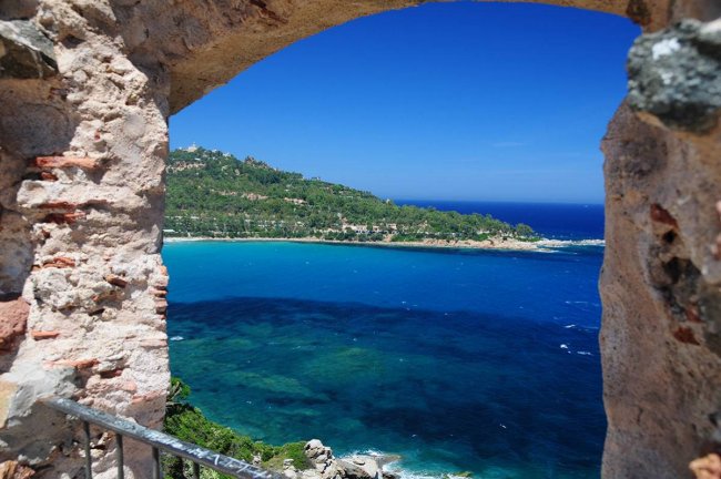 Vista sul mare attraverso un arco in pietra.