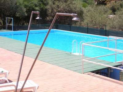 Piscina all'aperto con docce e sedie a sdraio.