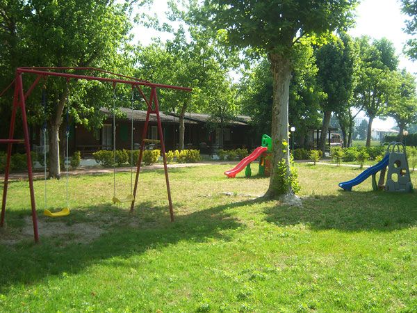 Un parco giochi con altalene e scivoli colorati su un prato verde.