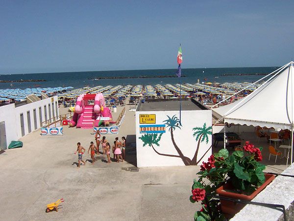 Spiaggia con molte sdraio, un gonfiabile rosa e vista sull'oceano.