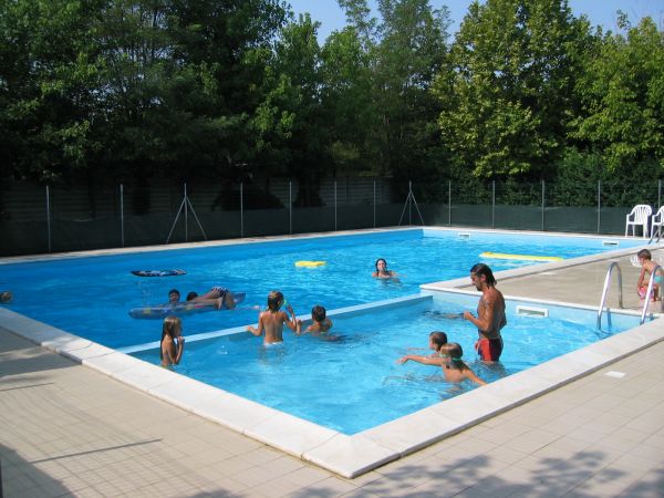 Piscina all'aperto con adulti e bambini che nuotano.