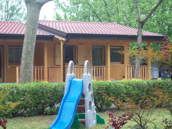 Scivolo blu in un giardino vicino a una casetta di legno.