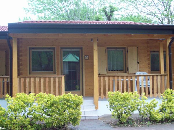 Ingresso di una casetta di legno con veranda e piante.