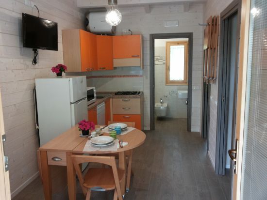 Cucina moderna con mobili arancioni e tavolo apparecchiato.