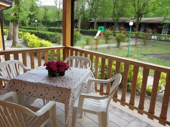 Tavolo con sedie su terrazza vista giardino verde.