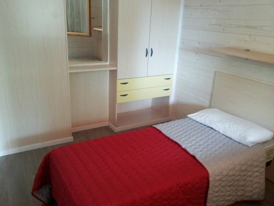 Camera singola con letto rosso e armadio chiaro.