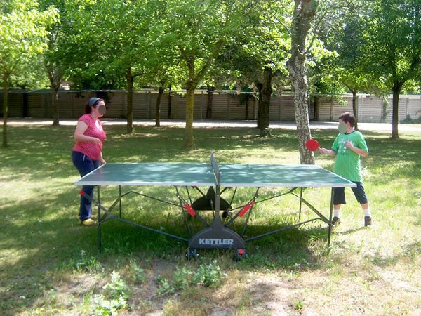 Persone giocano a ping pong all'aperto tra gli alberi.