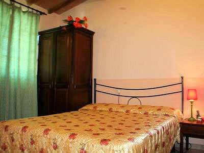 Stanza da letto con letto matrimoniale, armadio scuro, tenda verde e lampada da comodino.