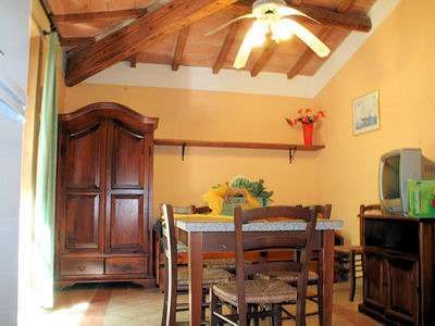 Sala da pranzo con tavolo e sedie in legno, ventilatore a soffitto e armadio.