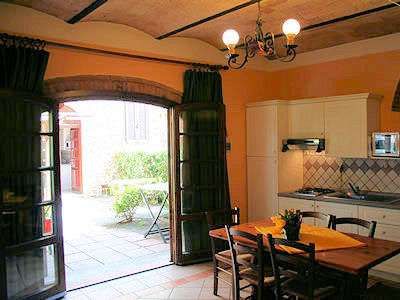 Cucina con tavolo e porte aperte verso un cortile con piante.