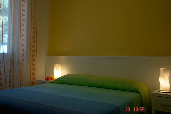 Letto matrimoniale con lampade su comodini.