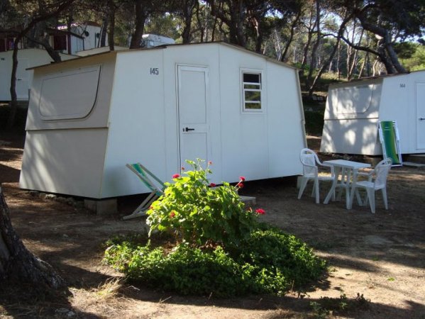 Casetta bianca con sedie vicino a un tavolo in un ambiente boschivo.
