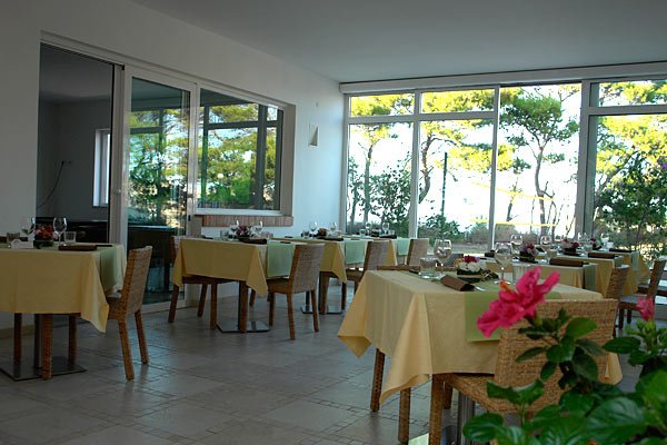 Ristorante luminoso con tavoli apparecchiati e vetrate ampie.
