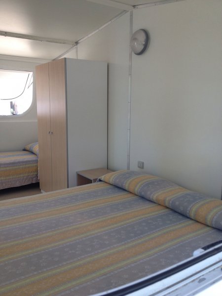 Camera con letti singoli, armadio e pareti chiare.