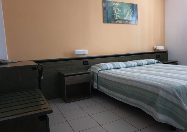 Camera da letto con pareti arancioni, letto matrimoniale e quadro floreale.