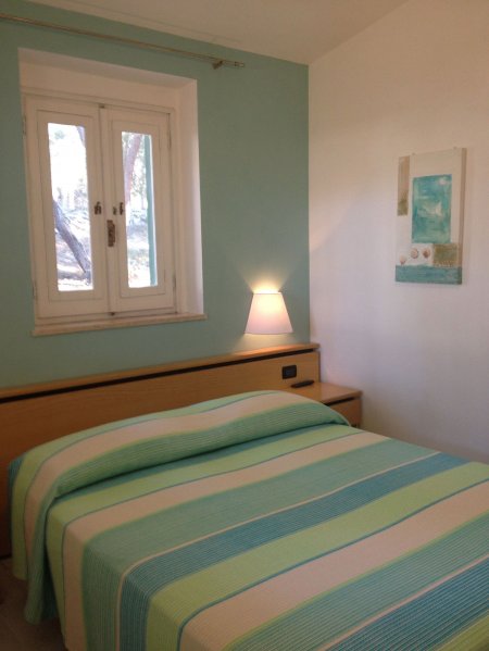 Camera con letto a righe e lampada accesa.