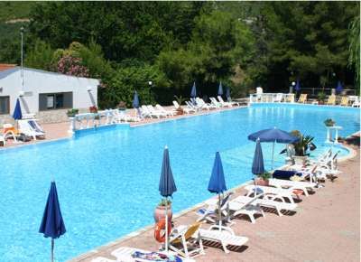 Piscina all'aperto con lettini e ombrelloni blu.