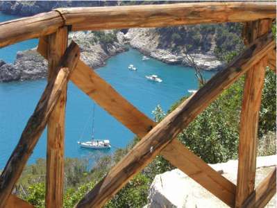Staccionata di legno con vista su barche in una baia turchese.