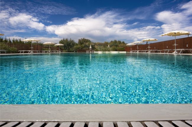 Una piscina con ombrelloni e cielo blu.