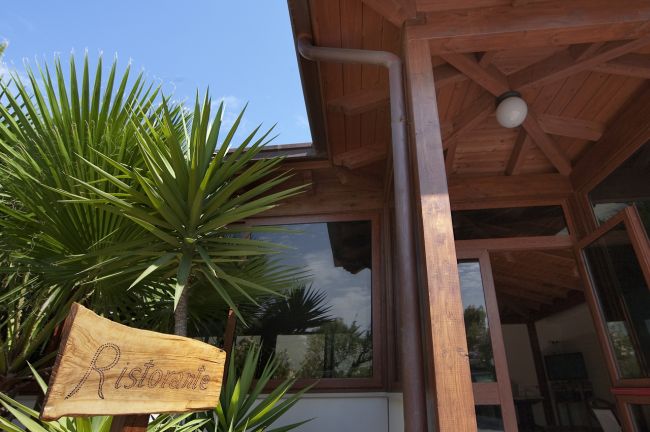 Insegna di un ristorante di legno e piante.
