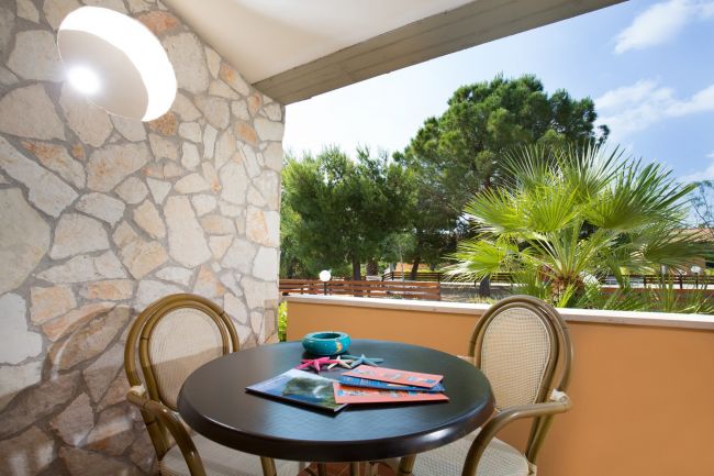 Tavolino con sedie su balcone di pietra.