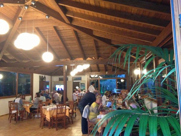Ristorante illuminato con travi in legno e clienti ai tavoli.