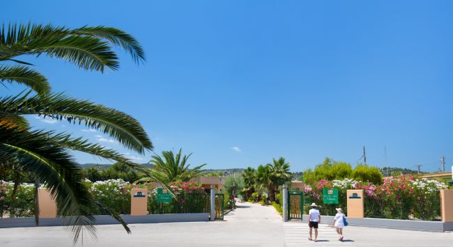 Entrata di un giardino fiorito con due persone che camminano.