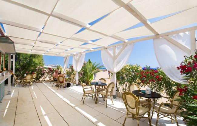 Terrazza coperta con sedie e tavolini vicino a fiori colorati.