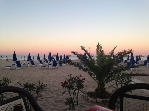 Spiaggia al tramonto con ombrelloni blu.
