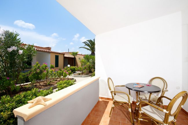 Veranda con tavolo, sedie e giardino fiorito.
