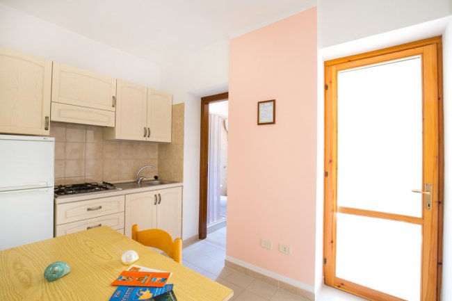 Cucina con tavolo di legno e porta luminosa.