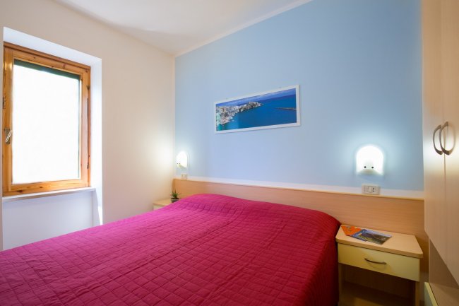 Camera da letto con letto matrimoniale e pareti blu e bianche.