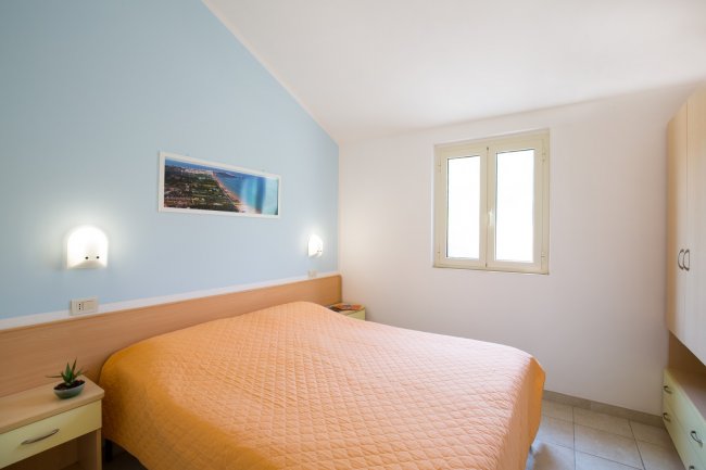 Camera da letto con letto matrimoniale e copriletto arancione.