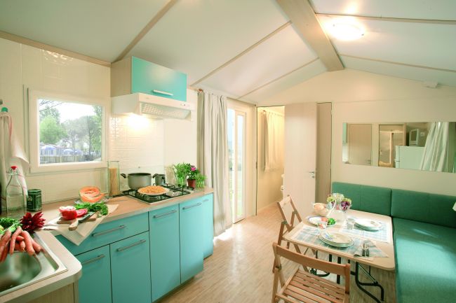 Interno di una cucina moderna con mobili turchesi e un tavolo apparecchiato.