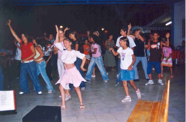 Gruppo di persone che ballano in un ambiente coperto, tra cui bambini e adolescenti.