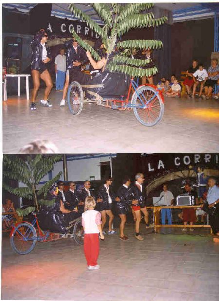 Esibizione su un palco con un gruppo di persone in costume e un carro decorato.
