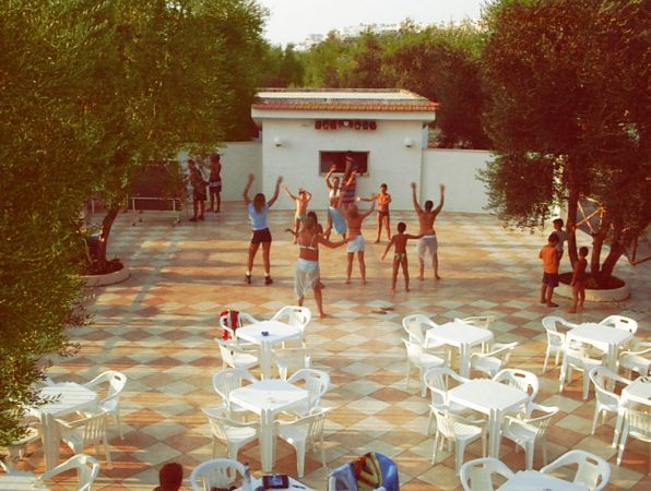 Persone che fanno esercizi all'aperto su una terrazza con sedie bianche.