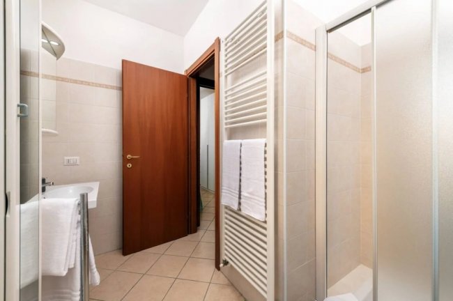 Bagno con doccia, lavandino e porta in legno.