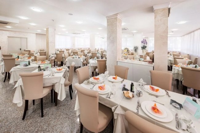 Ampia sala da pranzo con tavoli apparecchiati.