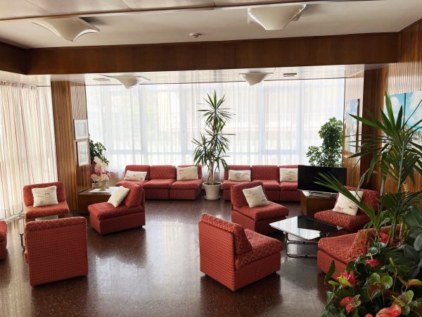 Salotto elegante con divani rossi e piante.