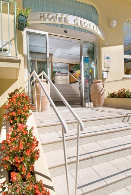 Ingresso di un hotel con gradini e fiori rossi.