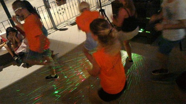 Persone che ballano in una pista con luci colorate.