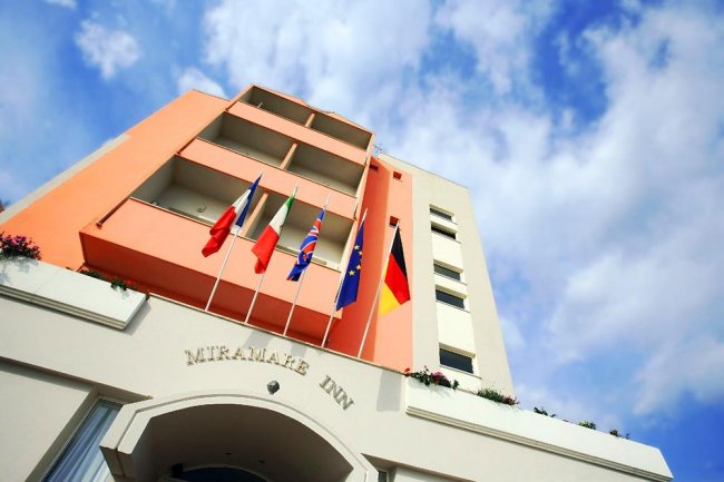 Edificio con bandiere nazionali e cielo nuvoloso.
