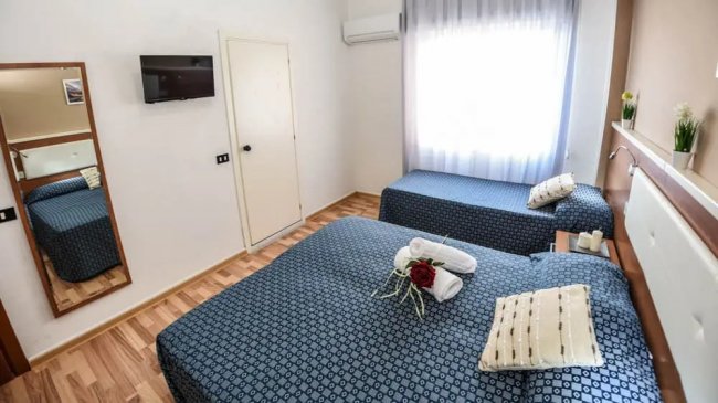 Camera con due letti, TV e finestra.