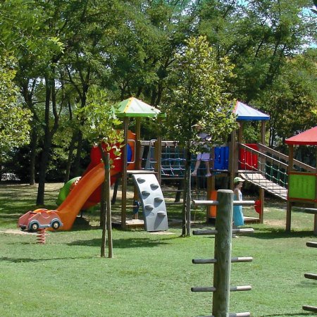 Parco giochi con scivoli colorati e alberi.