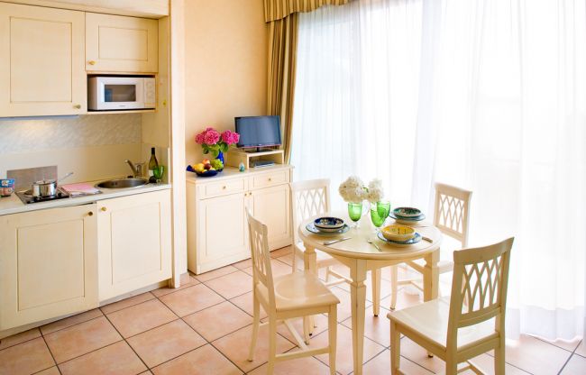 Cucina bianca con tavolo apparecchiato vicino a grandi tende.