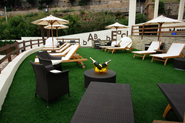 Terrazza con sdraio su prato sintetico.