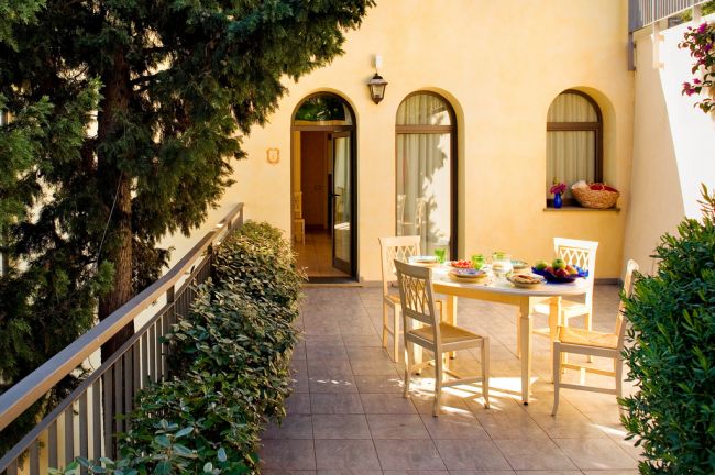 Cortile con tavolo, sedie e ingresso ad arco.