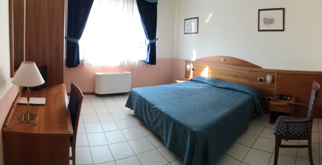 Stanza da letto con letto matrimoniale e scrivania.
